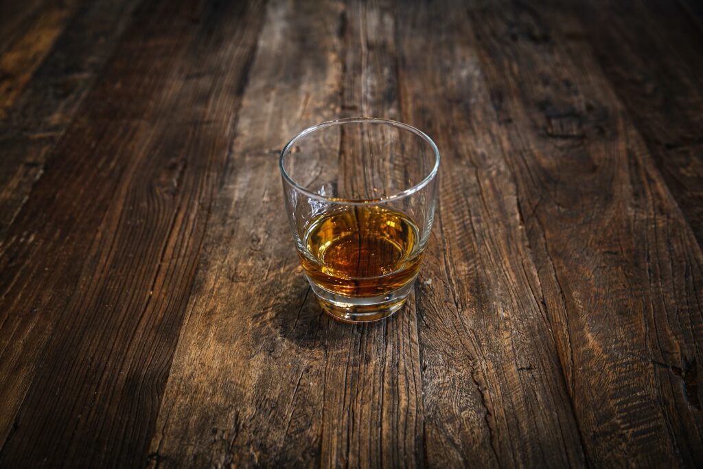 clear shot glass with brown liquid - WhiskeyandWhisky.com